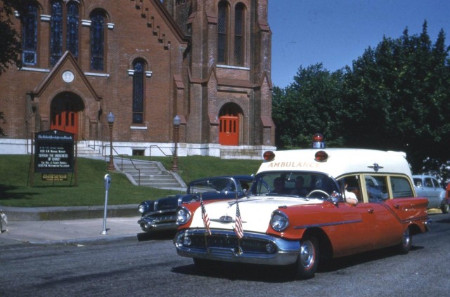 Oldsmobile Ambulance during a parade in the middle of town.