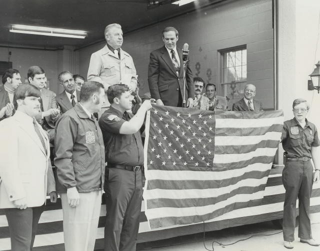 President Ayers stands on stage with local dignataries at the new building dedication in 1978.  Standing in front: (L-r) Larry Groseclose, Glenn Teeter, Wendell Higgins, and Ed Holbrook.