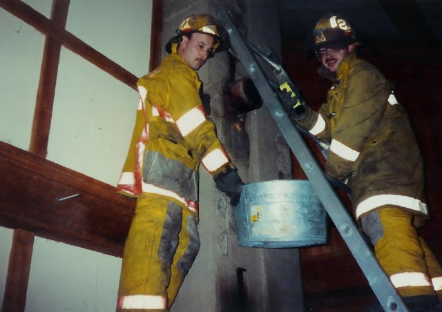 Firefighters Larry Herr and Bobby Stewart cleaning out a chimney.